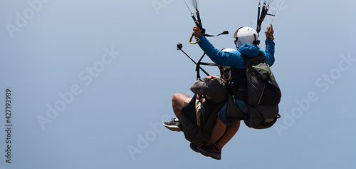 Tandem paragliding on background of blue summer sky