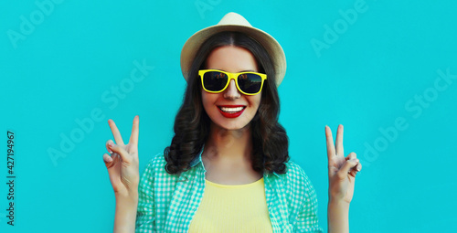 Portrait close up of happy smiling young woman wearing a summer straw hat on a blue background