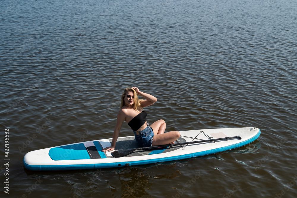 Naklejka premium Young attractive woman posing on paddle board