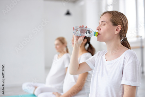 focus on blonde female drinking water after fitness