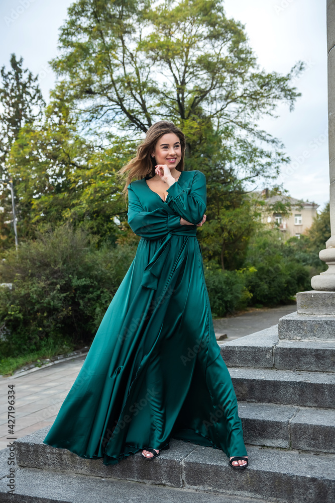 beautiful sensual girl wearing long elegant green dress standing on the building steps