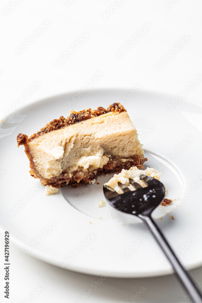 Bitten piece of vegan tofu cheesecake on white saucer. Healthy plant based dessert concept. Bitten piece of vegan tofu cheesecake on white saucer. Healthy plant based dessert concept.