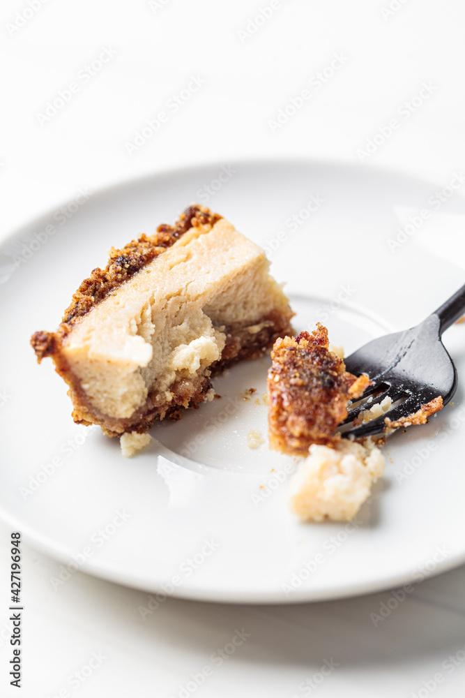 Bitten piece of vegan tofu cheesecake on white saucer. Healthy plant based dessert concept. Bitten piece of vegan tofu cheesecake on white saucer. Healthy plant based dessert concept.