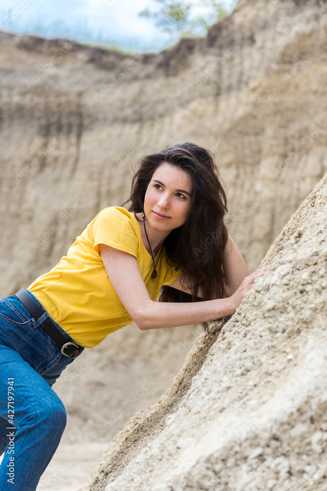 Pretty woman in casual clothes poses in sand canyon, relax at nature in summer time
