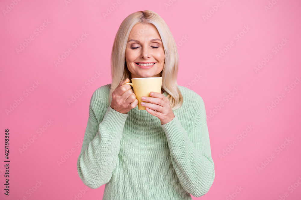 Photo portrait of old lady inhaling aroma of fresh coffee from yellow cup isolated on pastel pink colored background Photo portrait of old lady inhaling aroma of fresh coffee from yellow cup isolated on pastel pink colored background