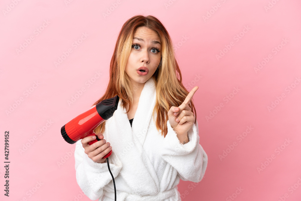 Teenager blonde girl holding a hairdryer over isolated pink background intending to realizes the solution while lifting a finger up Teenager blonde girl holding a hairdryer over isolated pink background intending to realizes the solution while lifting a finger up