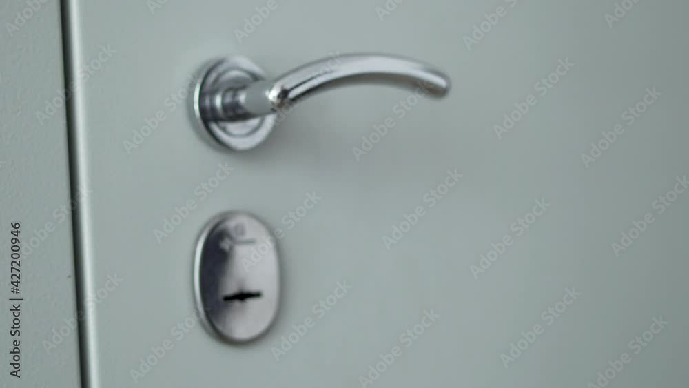 Hand Opens The Door Handle. Hand Inserts the Key into the Door Lock and Turns the Key in the Lock. Close-up of the Hand and the Door Handle. The Person Opens the Door to the Apartment and Enters. Hand Opens The Door Handle. Hand Inserts the Key into the Door Lock and Turns the Key in the Lock. Close-up of the Hand and the Door Handle. The Person Opens the Door to the Apartment and Enters.