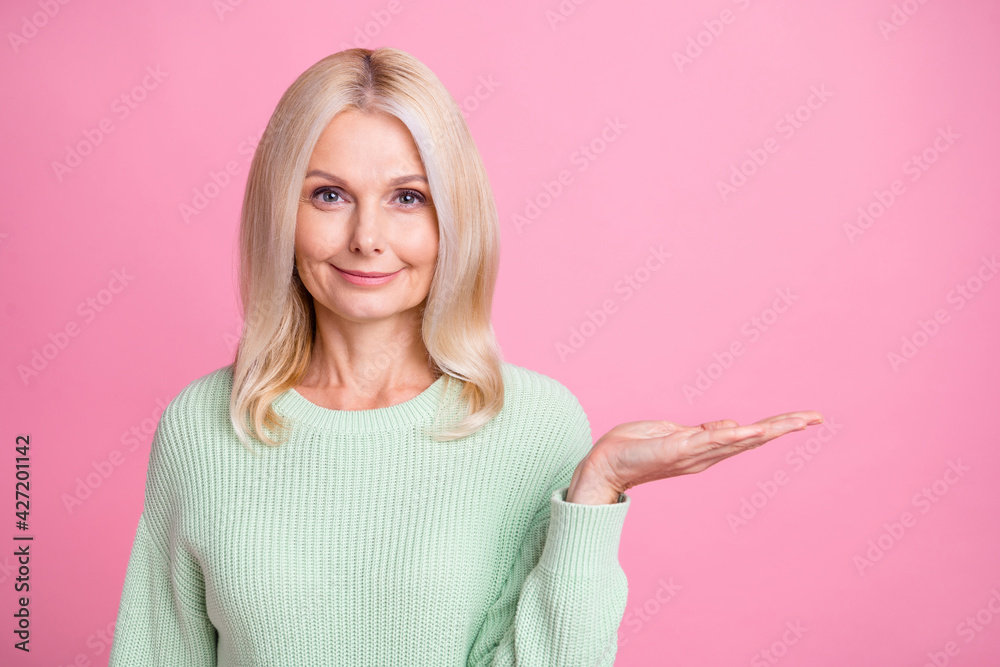 Photo portrait of old woman holding blank space in hand isolated on pastel pink colored background Photo portrait of old woman holding blank space in hand isolated on pastel pink colored background