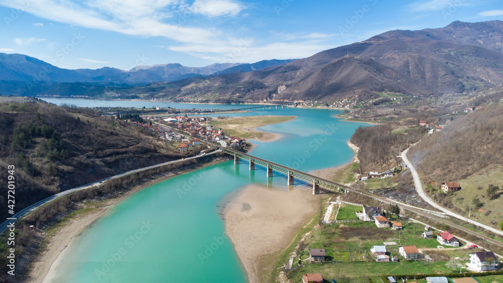 Aerial drone view of beautiful green lake, hills and villages. Railway bridge over the river. Landscape.
