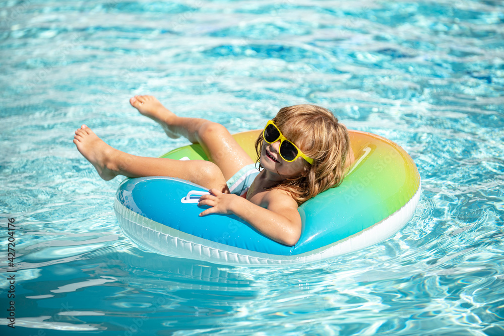 Summer vacation. Summertime kids weekend. Boy in swiming pool. Funny boy on inflatable rubber circle.