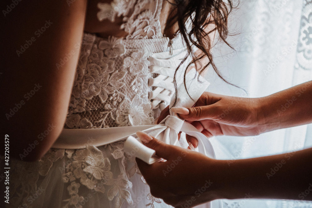 the bride wears a wedding dress, the godmother helps her the bride wears a wedding dress, the godmother helps her