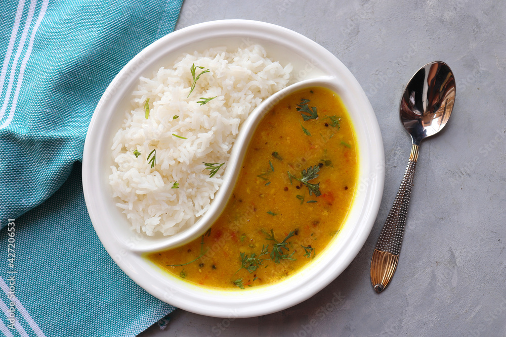Healthy nutritious Indian comfort food Dal Chawal thali or Dal Rice, also commonly known as Varan bhat in Marathi. Served in two way ceramic plate. Over white background with copy space. Healthy nutritious Indian comfort food Dal Chawal thali or Dal Rice, also commonly known as Varan bhat in Marathi. Served in two way ceramic plate. Over white background with copy space.