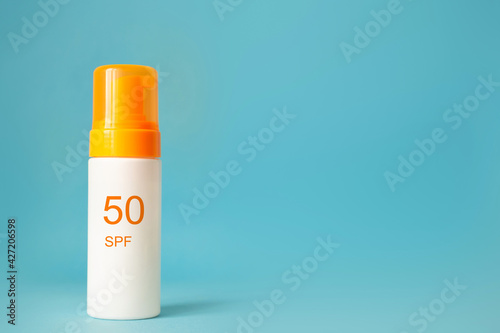 Sunscreen bottle with spf 50 cream or lotion on the aqua blue background with copy space. Sun protection, summer skin moisturizer
