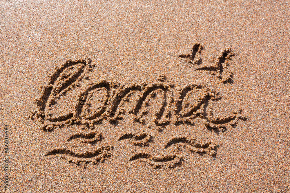 Fototapeta premium Finnish word Loma (vacation) handwritten on a sandy beach