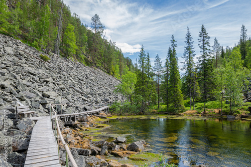 View of The Pyha-Luosto National Park in summer, rocks, stones, trees, wooden walkway and natural pond, Lapland, Finland