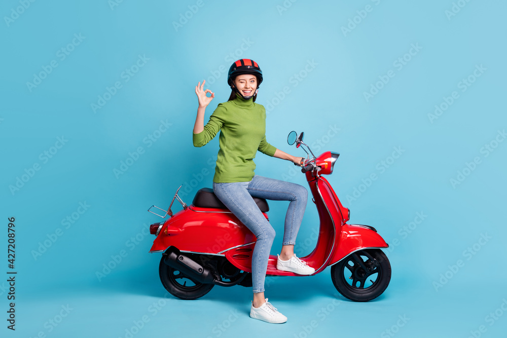 Full body profile photo of attractive person sit on bike fingers show okey symbol isolated on blue color background Full body profile photo of attractive person sit on bike fingers show okey symbol isolated on blue color background