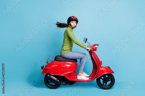 Profile side view portrait of attractive amazed cheerful girl riding moped pout lips way isolated over bright blue color background