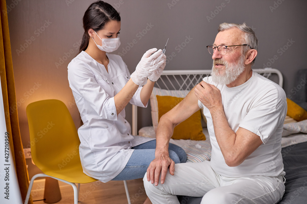 Obraz premium Female Doctor Preparing Syringe For Making Injection To Elderly Man