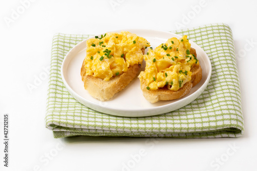 Scrambled eggs served on bread toast on white background