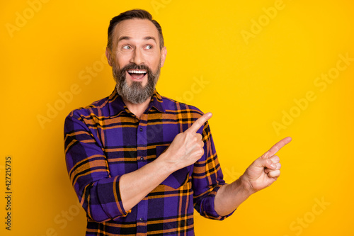 Portrait of attractive funky cheerful guy demonstrating copy empty space ad isolated over bright yellow color background