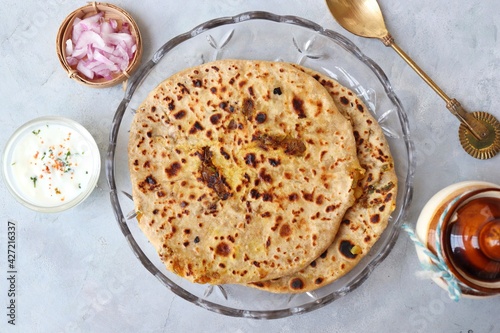 Indian traditional Hot Onion Paratha with yogurt. Indian onion stuffed Flatbread. also known as Pyaz ke parathe in Hindi. over a light background with copy space.