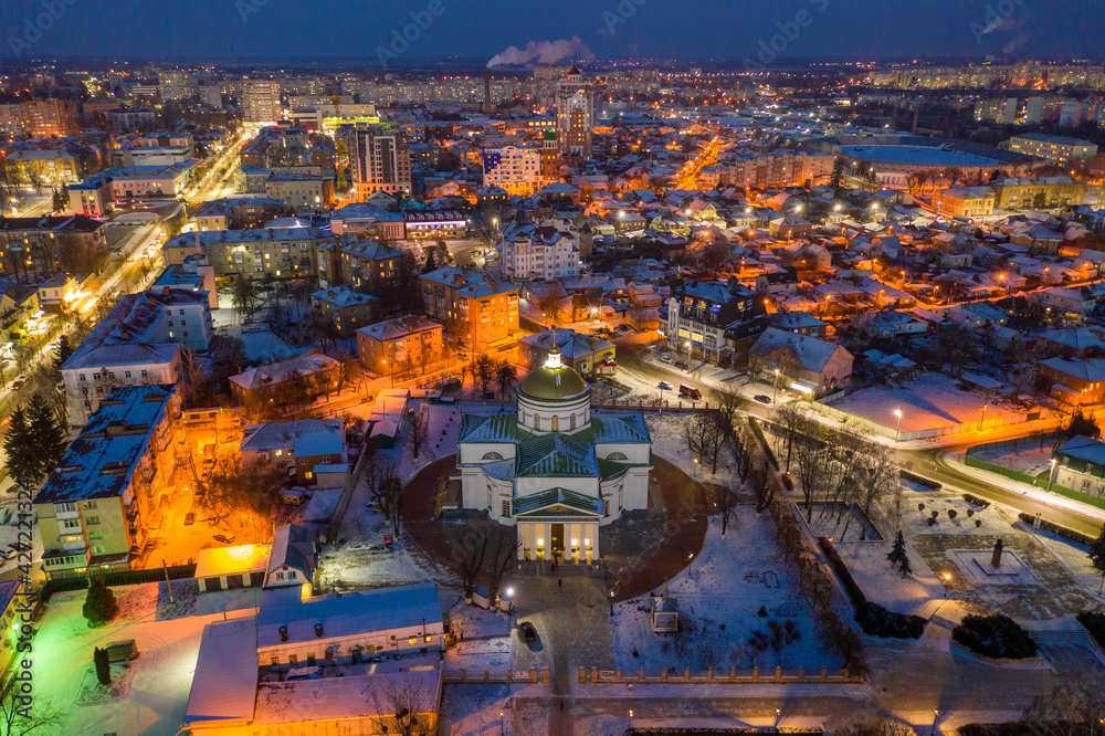 Naklejka premium Beautiful evening top view of the city. Evening, night illumination in the city. Winter city in the snow.
