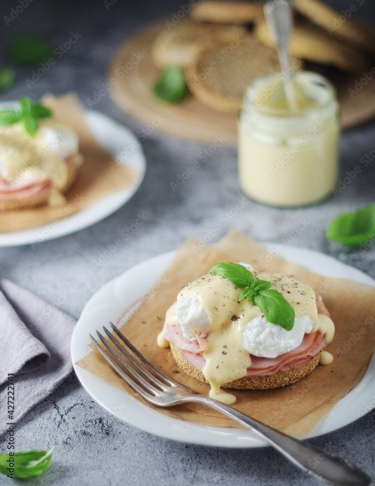 Egg benedict sandwiches - muffin with poached egg, ham and hollandaise sauce Egg benedict sandwiches - muffin with poached egg, ham and hollandaise sauce