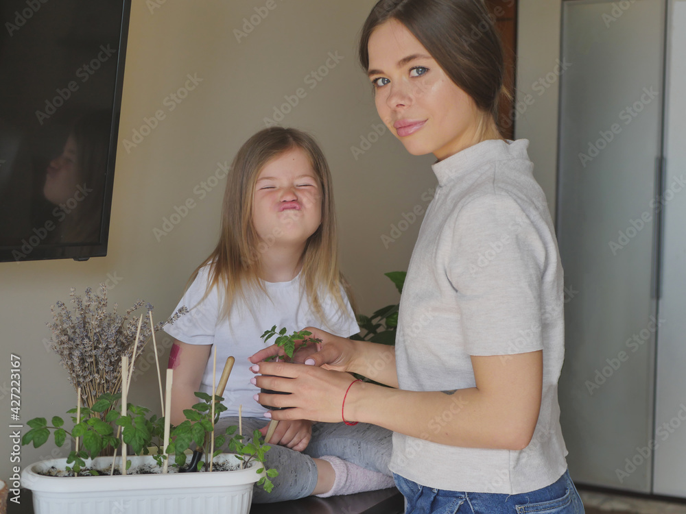 young beautiful mother with her little daughter are engaged in gardening. plant lovers enjoy their hobby. family values and lifestyle. young beautiful mother with her little daughter are engaged in gardening. plant lovers enjoy their hobby. family values and lifestyle.