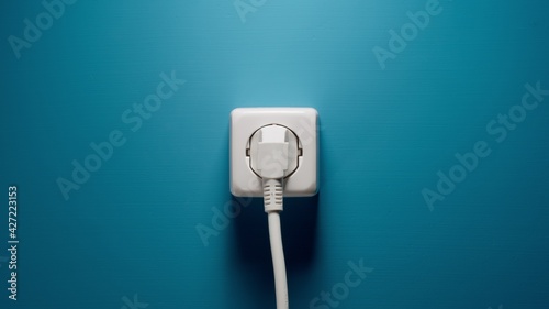 Plugged into an electrical outlet on a blue wall