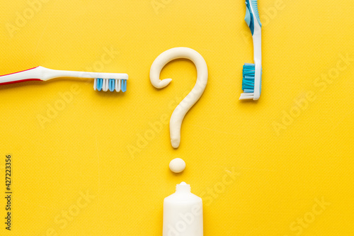 Question mark of toothpaste with toothbrush, top view. Oral care and hygiene