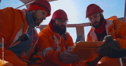Lifeguards using tablet studying map sitting in boat