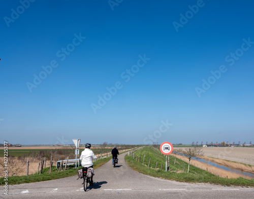 people ride bicycle on sunny spring day in dutch countryside of zeeland photo