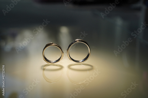 two wedding gold rings reflected in the mirrored surface