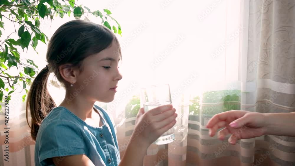 The child drinks water from a glass. Selective focus. The child drinks water from a glass. Selective focus.
