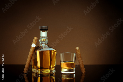 close up view of cigar, bottle of cognac and a glass aside on brown back.  © Dmitry Ersler