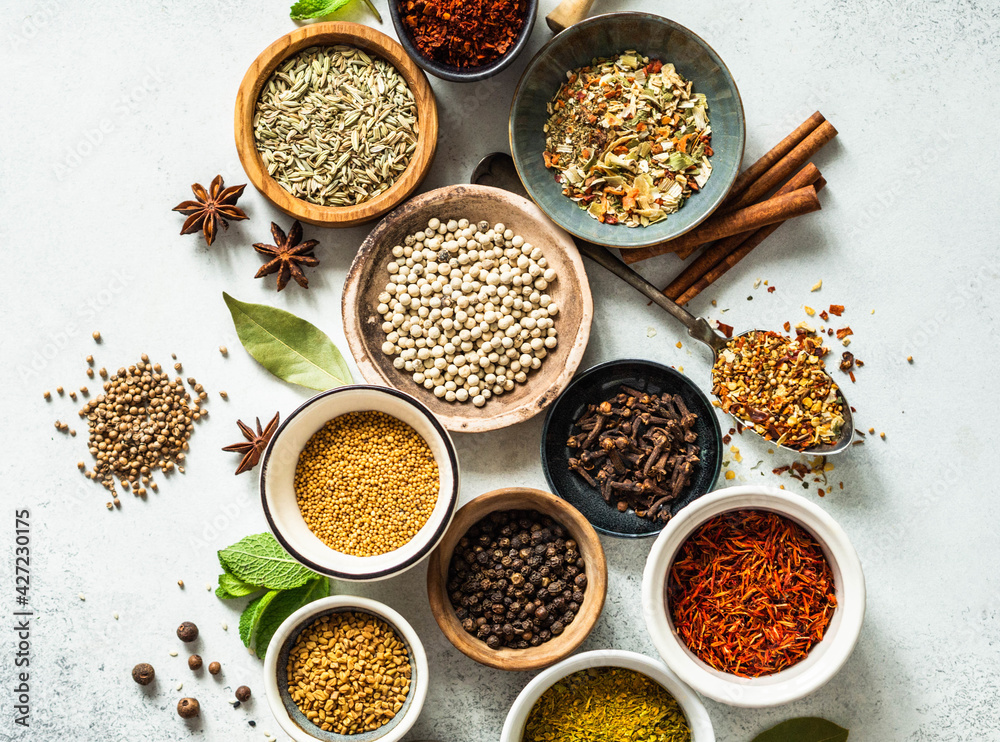 Various dry spices in small bowls flat lay on grey background. Various dry spices in small bowls flat lay on grey background.