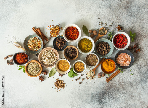 Various dry spices in small bowls and raw herbs flat lay on grey background. © senteliaolga
