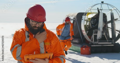 Rescuers on an air-cushion boat patrolling lake in winter