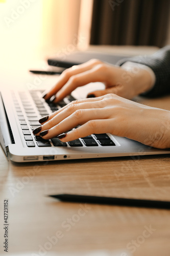 Woman working at home with laptop is typing text. Female hands on the keyboard