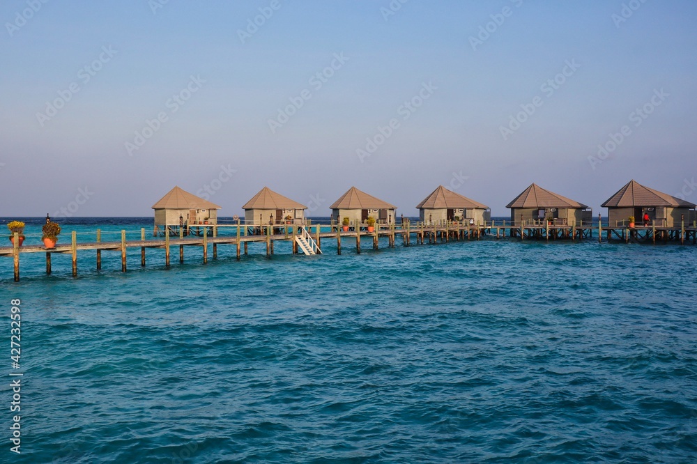 Golden Hour View of Water Villas in Maldives. Overwater Bungalow, Wooden Pier and Laccadive Sea in Maldivian Resort.