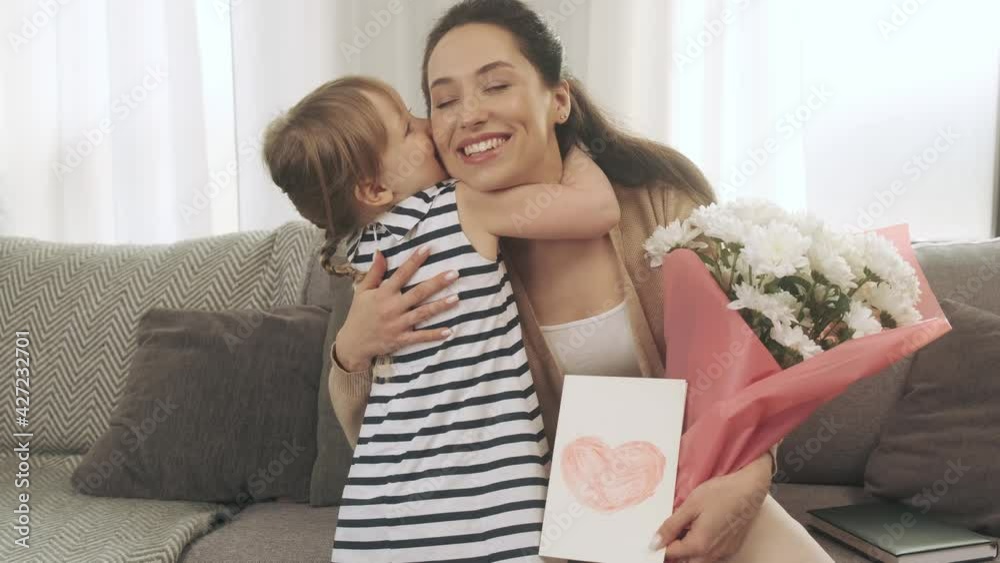 Daughter gives her mother a card with a heart and flowers. Mother's Day girt. Little girl congratulates her mommy Daughter gives her mother a card with a heart and flowers. Mother's Day girt. Little girl congratulates her mommy