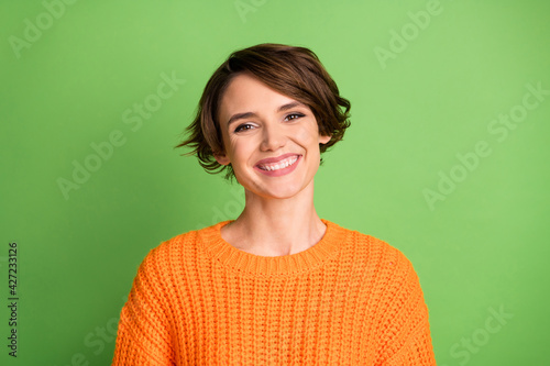 Portrait of optimistic brunette lady wear orange sweater isolated on pastel green color background
