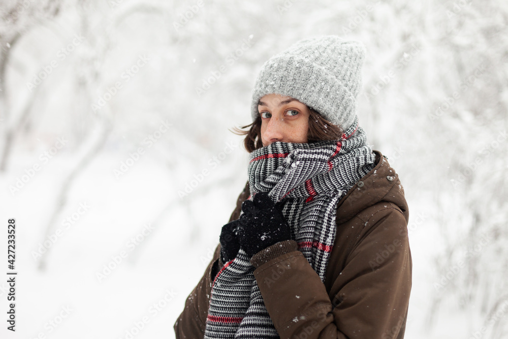 Young woman in warm clothes in winter snowy weather outdoors