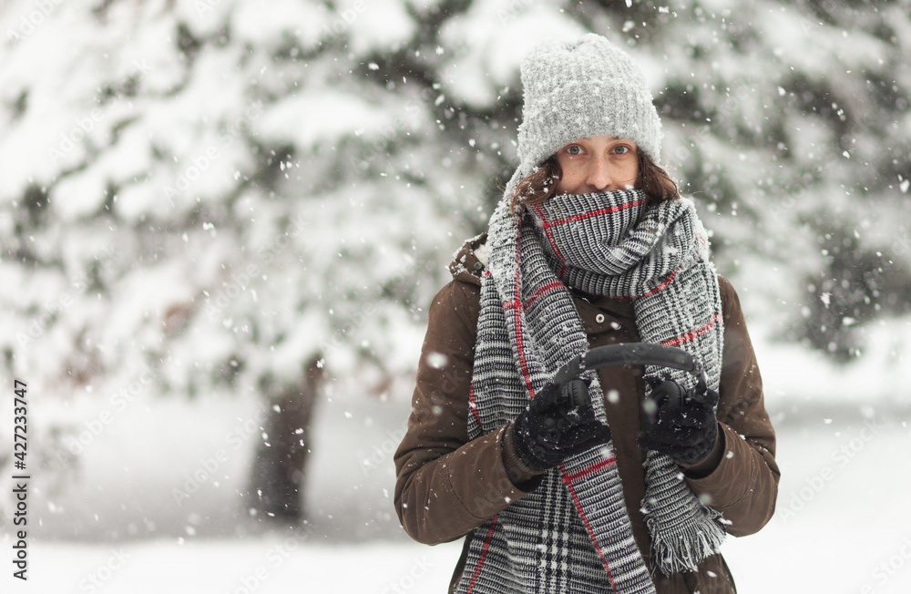 Fototapeta premium Portrait of attractive woman in warm clothes in winter snowy weather outdoors