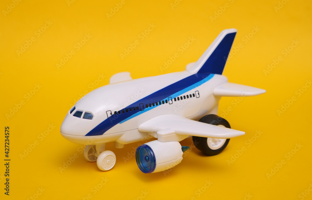 Fototapeta premium Toy passenger plane on yellow background. Travel concept.