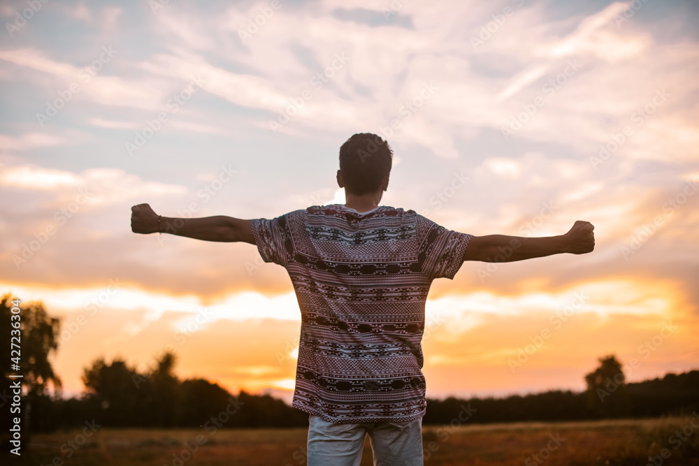 Man in the field at sunset enjoy life smiling, happy with victory,  good news, screams, freedom.