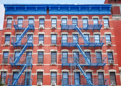 Old red brick building with blue iron fire escapes, New York City, USA.