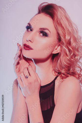 Blonde in silver and diamonds  obesity  earrings  rings. Woman with beautiful long nails and manicure. Girl with shiny makeup in neon. Glitter makeup  red lips