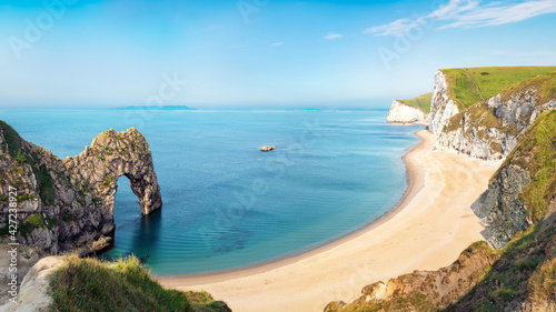 Aerial view of Durdle Door natural formation at UNESCO heritage Jurassic Coast. The Isle of Portland can be seen on the horizon. Copy space in blue sky. photo
