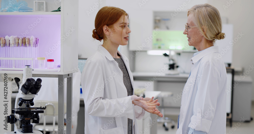 Young female scientist discussing result of virus research with supervisor in laboratory Young female scientist discussing result of virus research with supervisor in laboratory